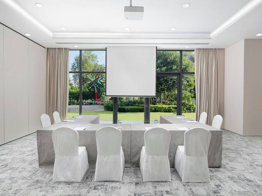 A conference room with a large table, chairs, and a projector screen.