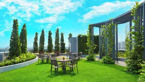 A rooftop garden with a seating area, potted plants, and a pergola structure.