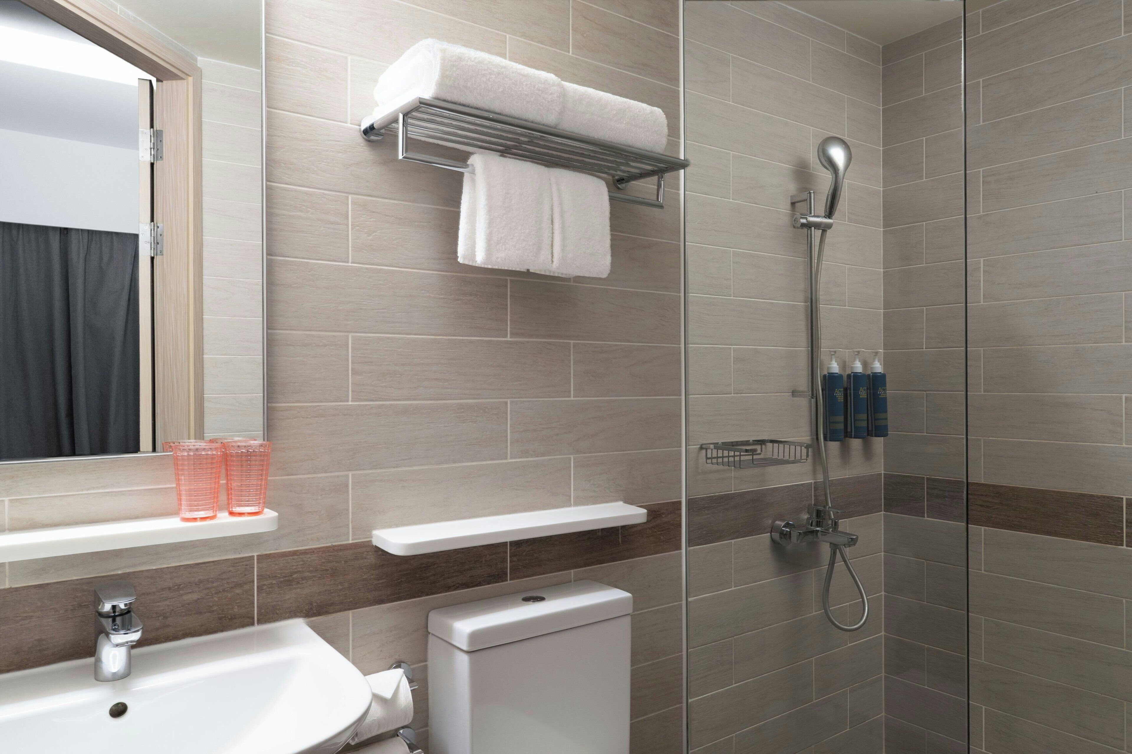 Un baño moderno con ducha, inodoro, lavabo y toallero.
