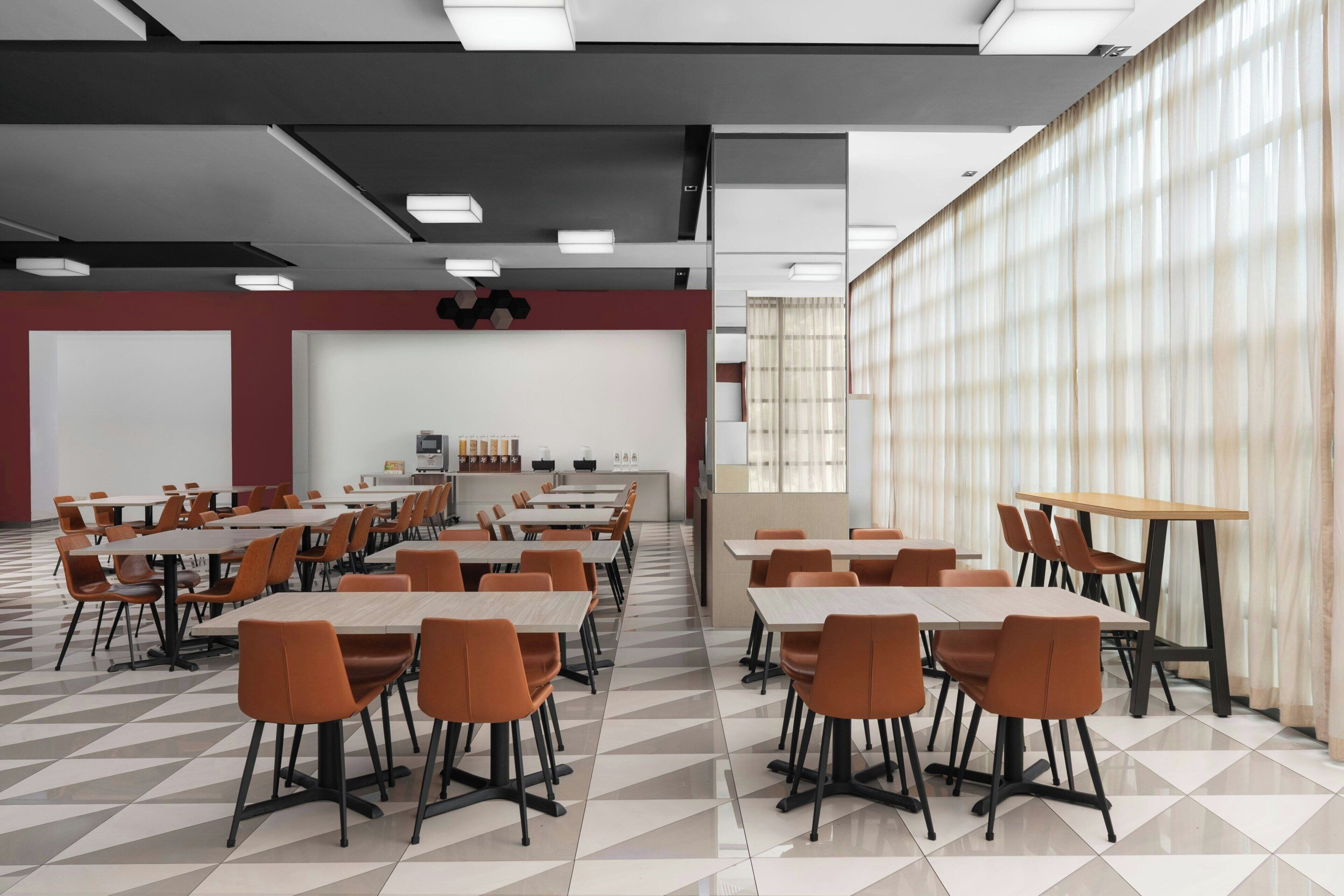 Una sala de conferencias con varias mesas y sillas, una pizarra y una pantalla de proyección.