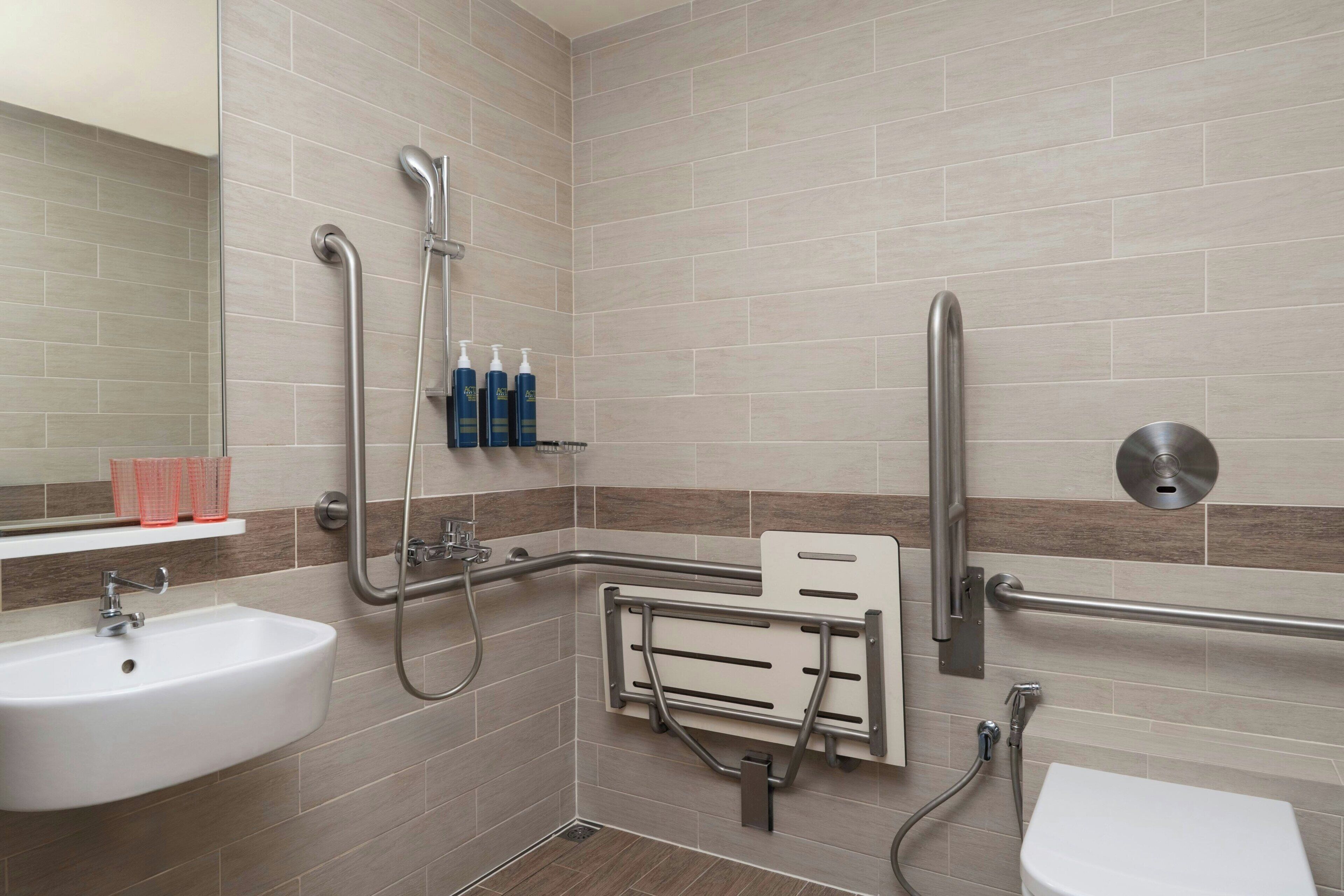 Une salle de bain équipée d’une douche, d’un lavabo et de toilettes. Des barres d’appui ont été installées pour plus de sécurité.