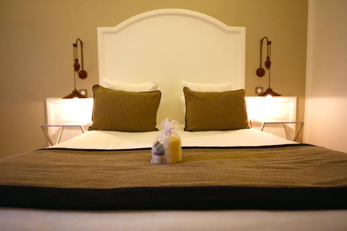 A neatly made bed with a white headboard, two brown pillows, and a small gift bag on the bed.