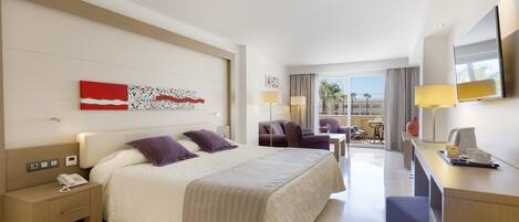 Habitación de hotel con una cama grande, un escritorio con lámpara, una silla y vistas al exterior.