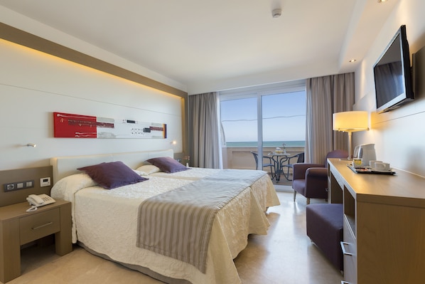 A hotel room with a bed, bedside table, lamp, TV, and a balcony with a view.