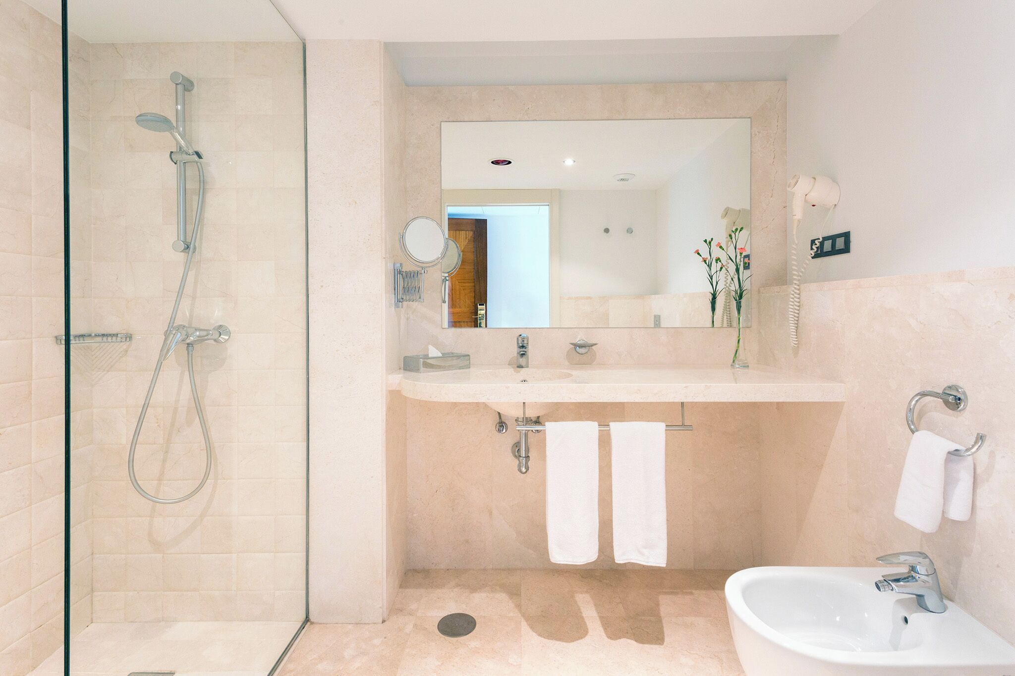 Une salle de bain moderne avec une douche à parois de verre, un lavabo et un miroir.