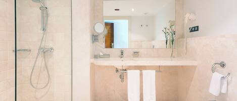 Une salle de bain moderne avec une douche à parois de verre, un lavabo et un miroir.