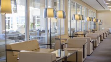 Un moderno vestíbulo de hotel con filas de asientos, ventanas amplias y lámparas de pie.