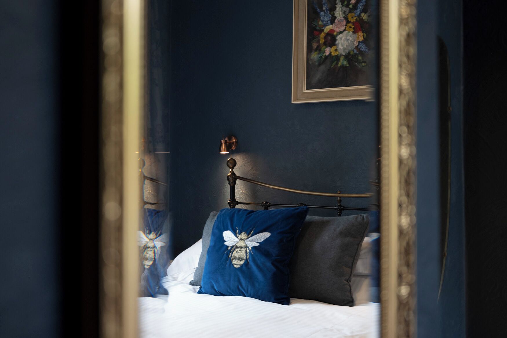 A bedroom with a bed, pillows, a headboard, and a painting on the wall.