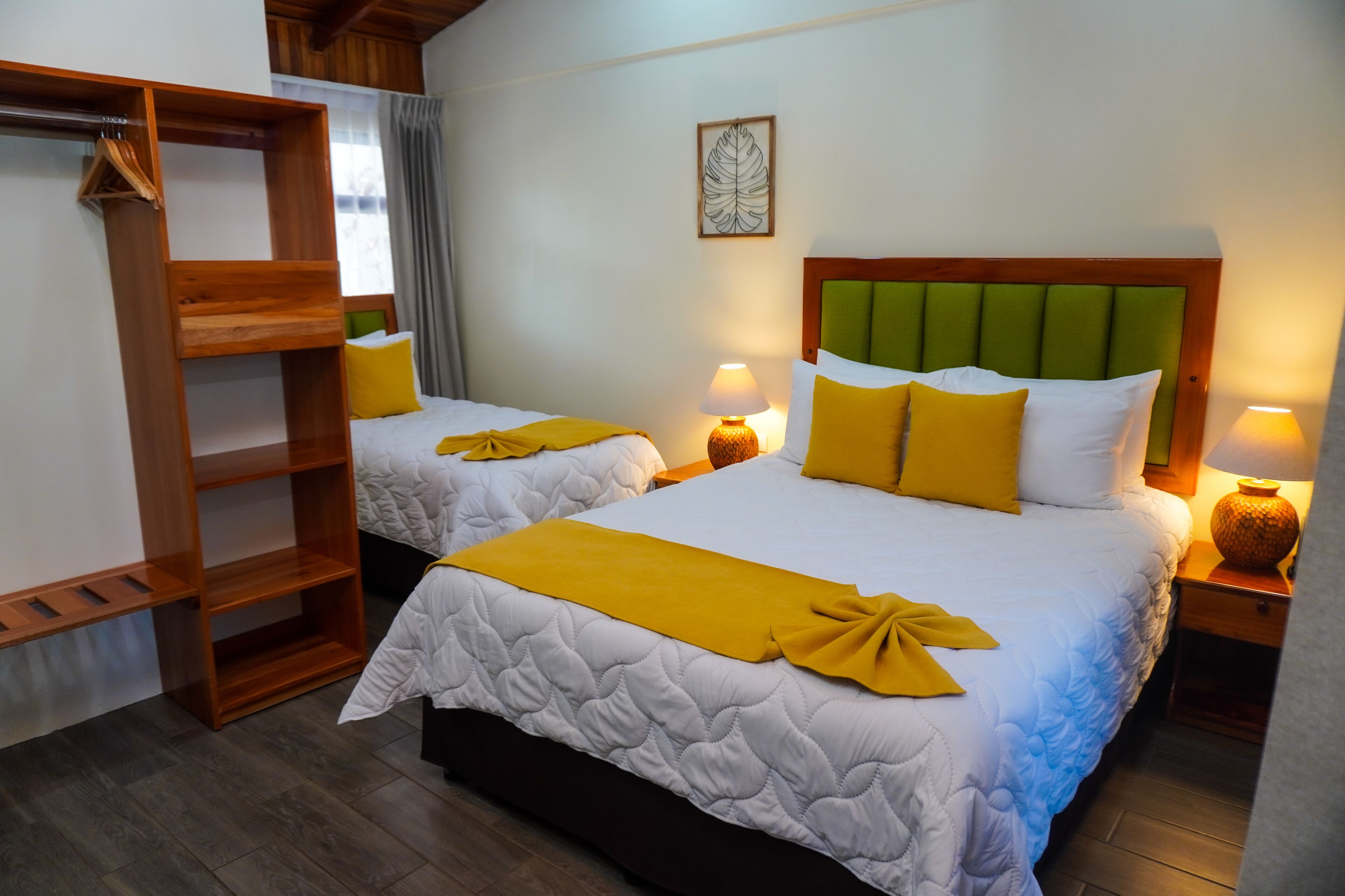 A hotel room with two beds, wooden headboards, and bedside lamps.