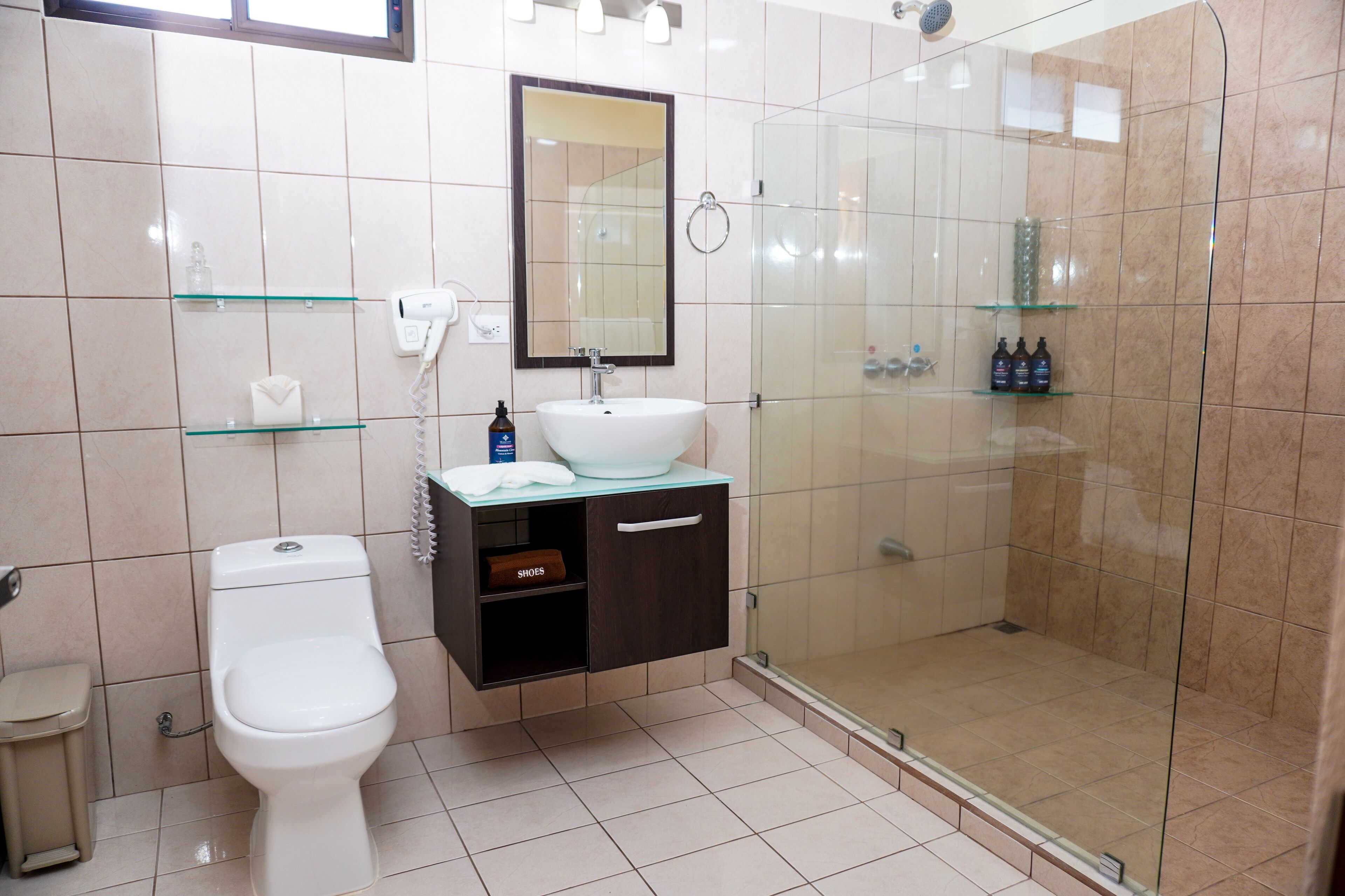 A modern bathroom with a toilet, a sink, a glass shower enclosure, and a vanity with a mirror.