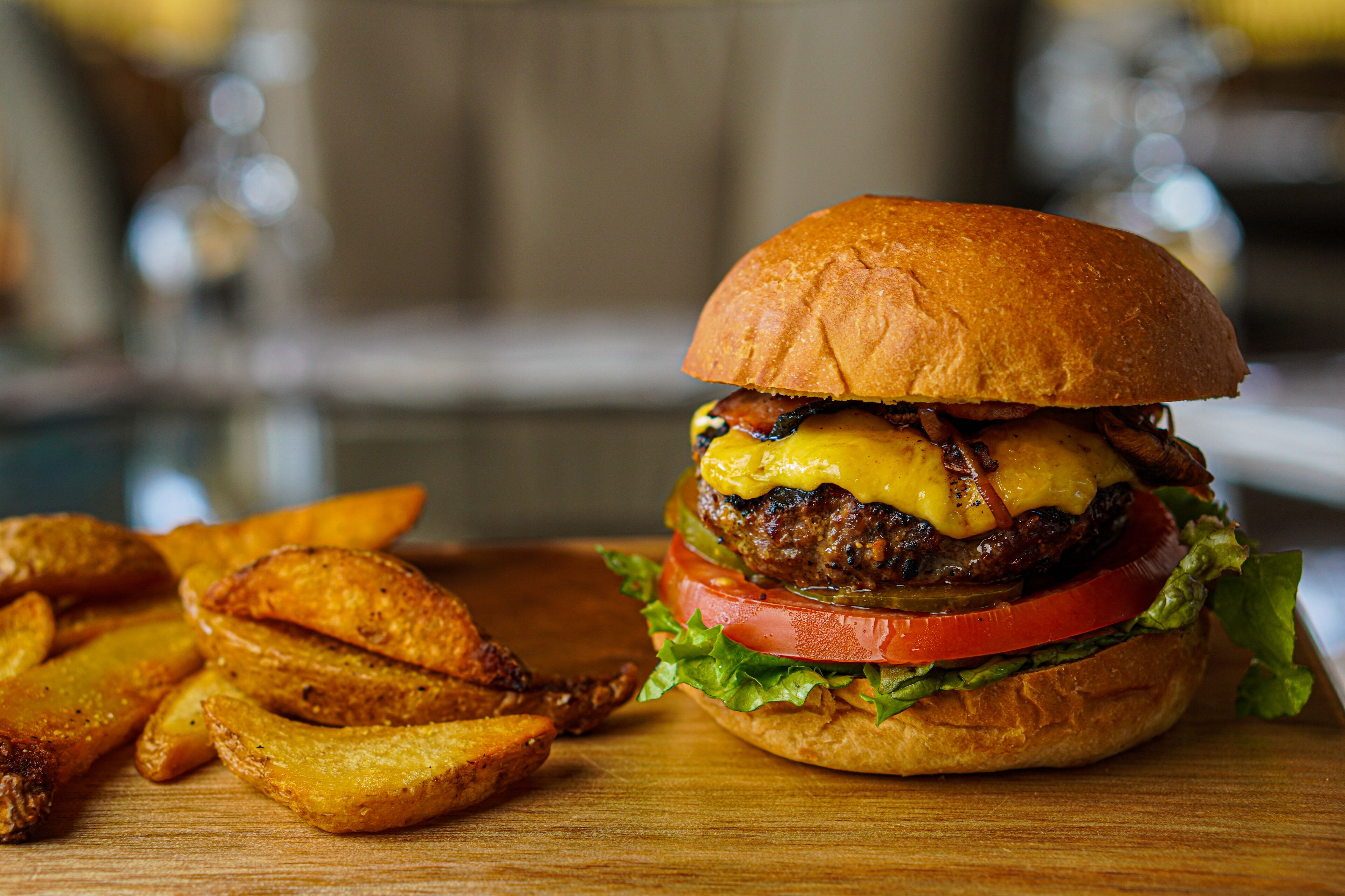 Una hamburguesa con pan, queso, lechuga, tomate y una hamburguesa de carne, acompañada de papas fritas.