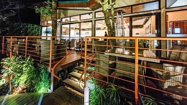 A modern building with a glass facade, a wooden staircase, and indoor plants. - Sibu Boutique Hotel (Monteverde)