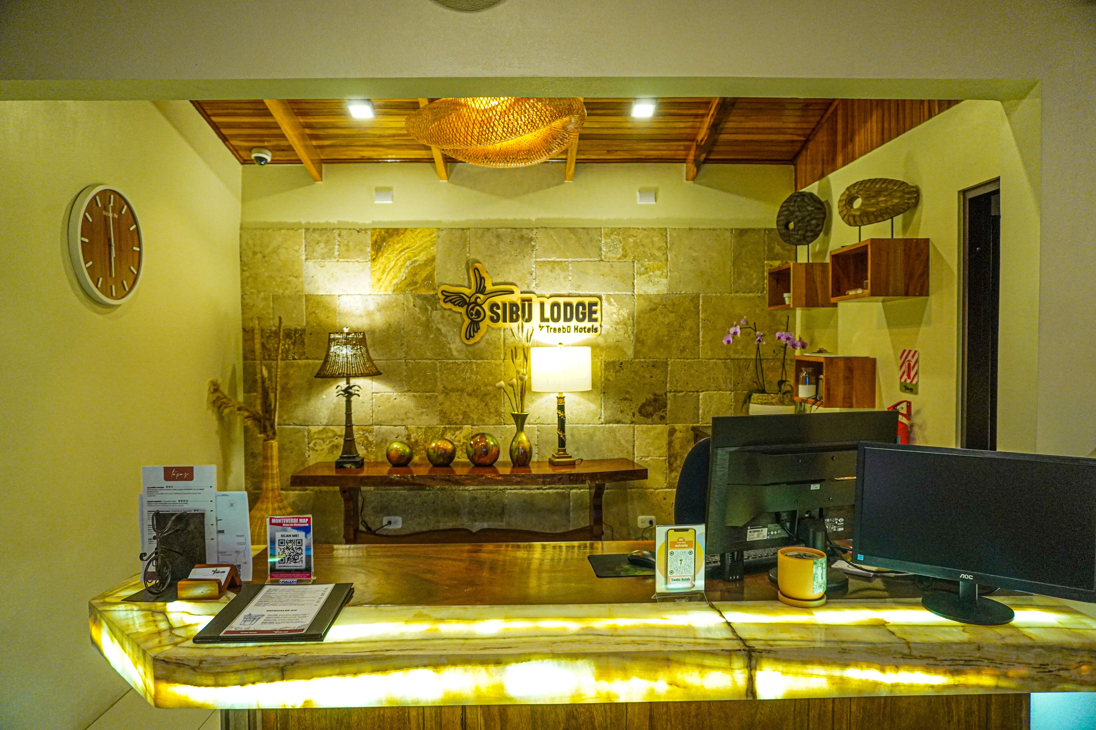 Una recepción con pared de piedra, un reloj y un cartel para Sibu Lodge.