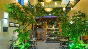 An indoor garden with seating areas, a staircase, and hanging lights. - Sibu Boutique Hotel (Monteverde)