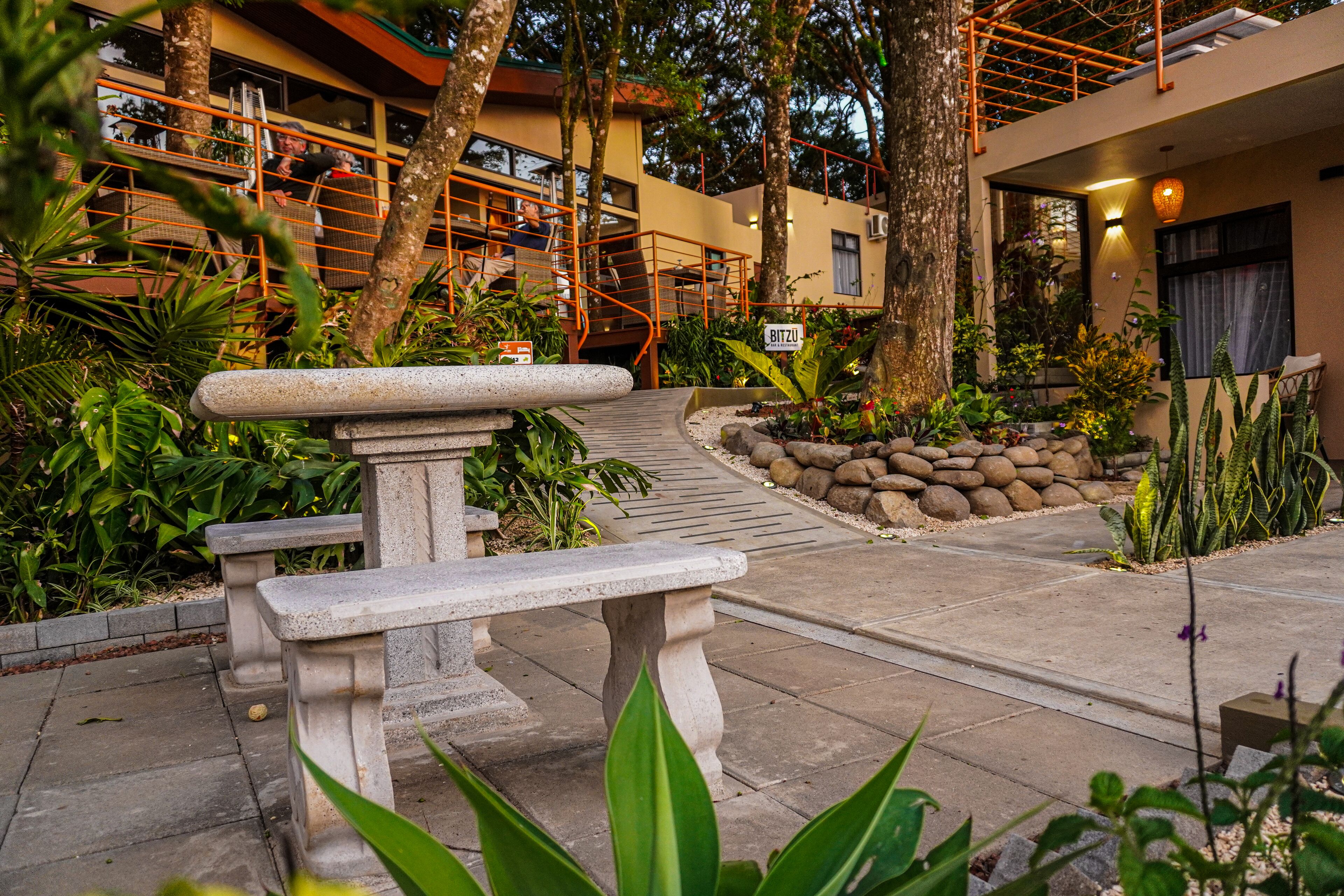 A courtyard with a stone bench, a staircase, and a sign reading "BITZU".