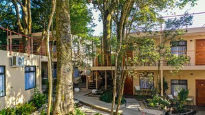 A courtyard with a staircase leading to a balcony, surrounded by trees and plants. - Sibu Boutique Hotel (Monteverde)
