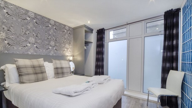 A modern hotel room with a large bed, a seating area, and a view of the outside.