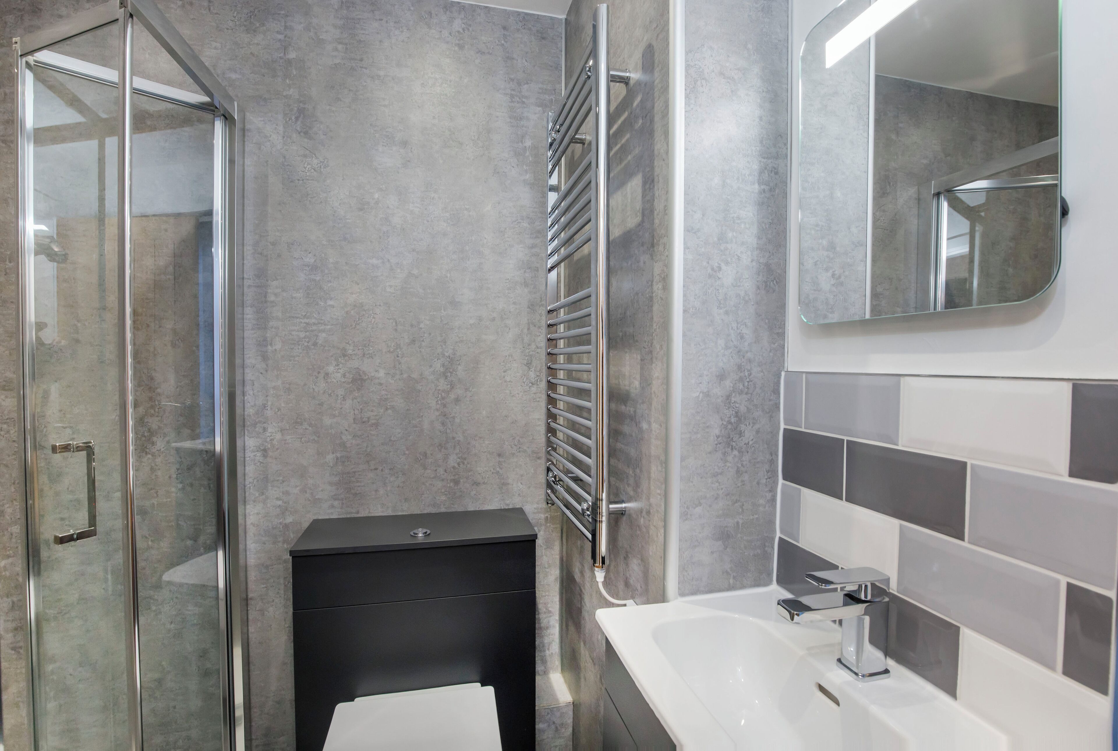 Une salle de bain moderne avec une douche à parois de verre, un meuble-lavabo noir, une baignoire blanche et un grand miroir.