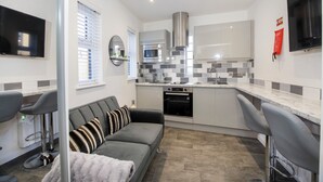 A modern kitchen with a grey sofa, a TV, and a microwave.