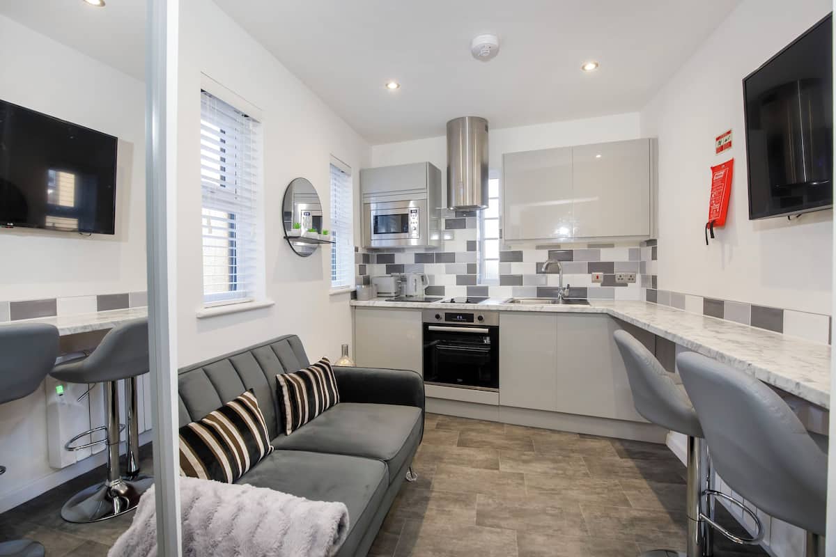 A modern kitchen with a grey sofa, a TV, and a microwave.