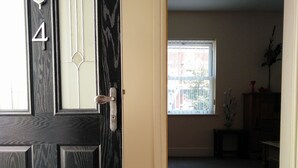Una porta nera con il numero 4 e un pannello di vetro, che dà accesso a una stanza con finestra e pavimento tappezzato.