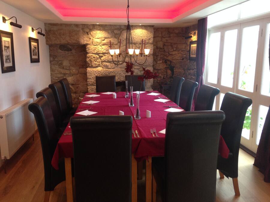 Un comedor con pared de piedra, un candelabro y una mesa dispuesta para seis personas.