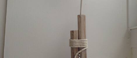 A wooden sculpture of a bird with a long beak, a rope tied around a wooden post, and several seashells on a white surface.