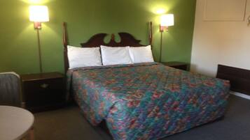 A neatly made bed with a floral bedspread, two bedside lamps, and a wooden headboard.