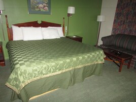 Una habitación de hotel con una cama grande, un sofá y dos lámparas de noche.