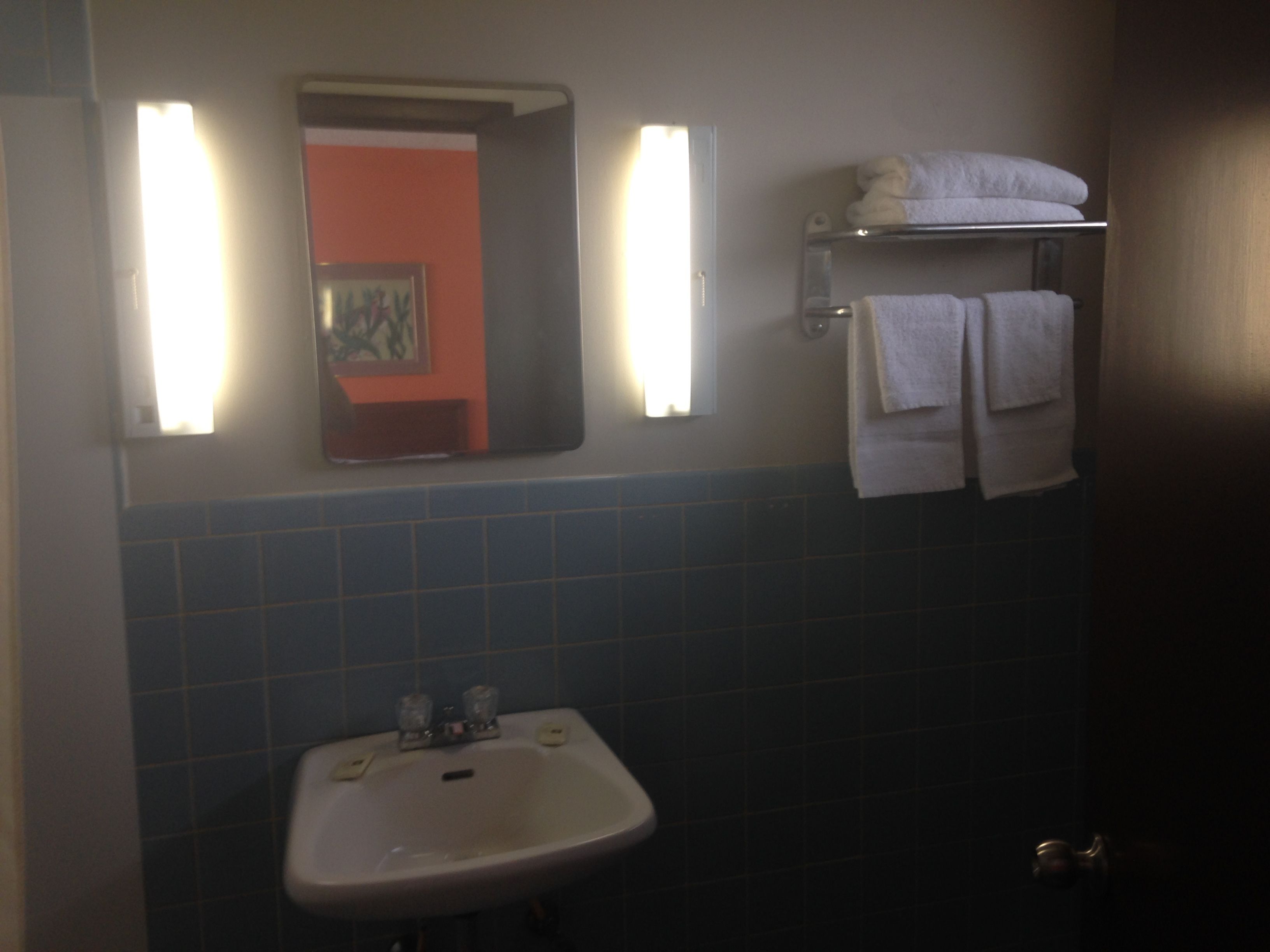 A bathroom with a sink, mirror, and towel rack.