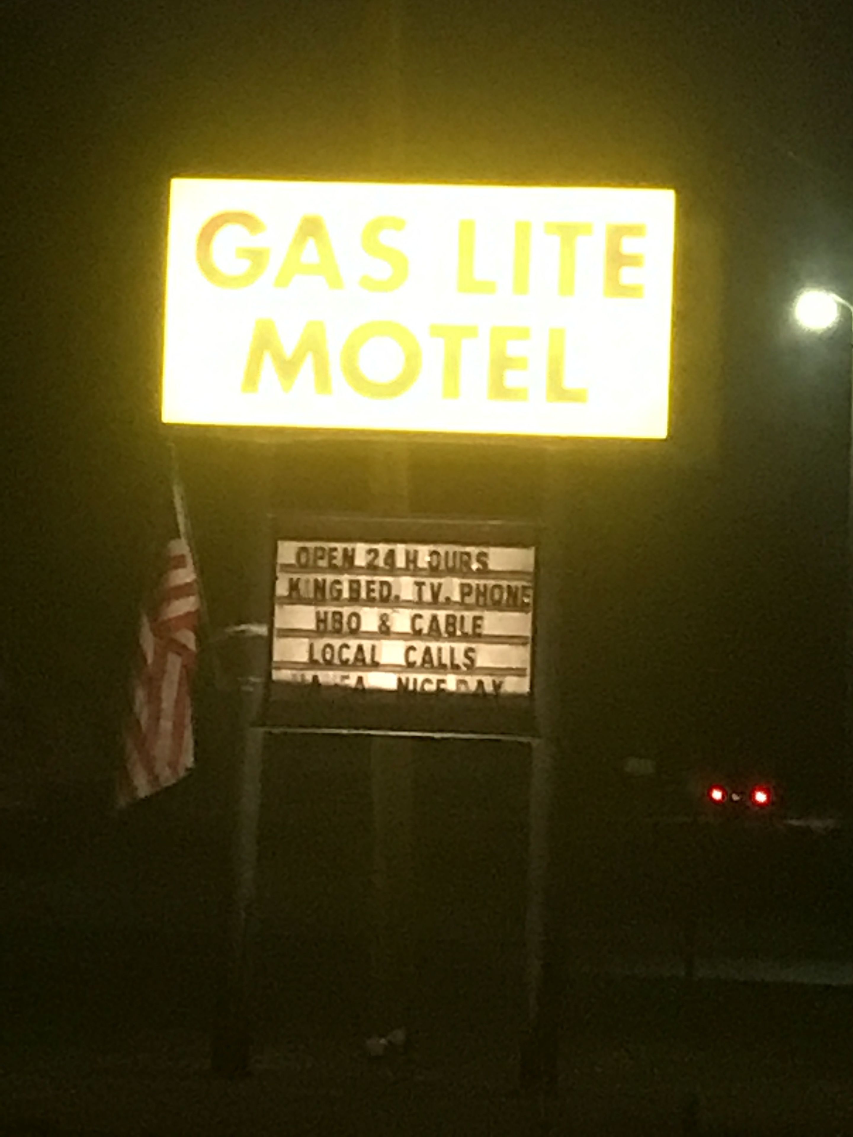 A sign for the Gas Lite Motel, indicating it is open 24 hours, has KingBed, TV, phone, HBO & cable, and local calls.