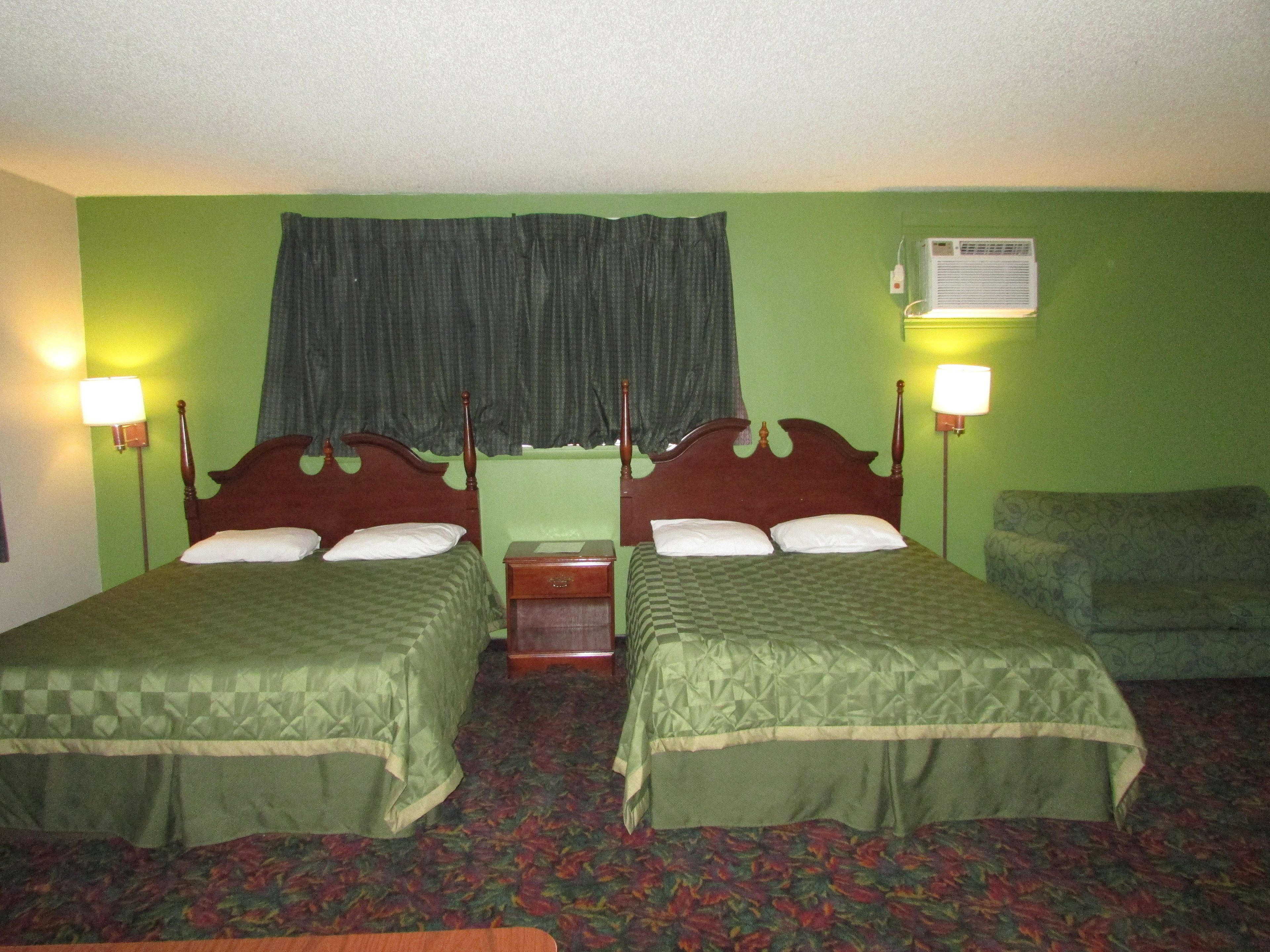 A twin room with two beds, a green wall, a patterned carpet, and a green curtain.