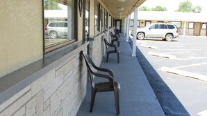 A row of plastic chairs outside a building with a brick wall and windows. - Gas Lite Motel (Lawrenceville)
