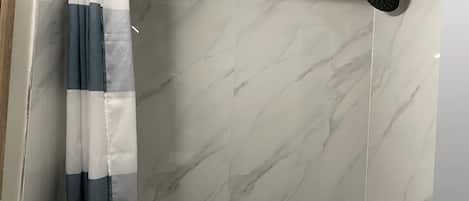 A bathroom with a shower, a curtain, and a door with a handle.