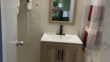 Un baño con un mueble de madera, un lavamanos blanco, un secador de pelo y un espejo.