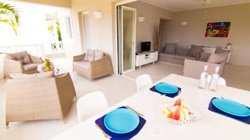 A dining area with a table set for four, a sofa, and a television in the background.