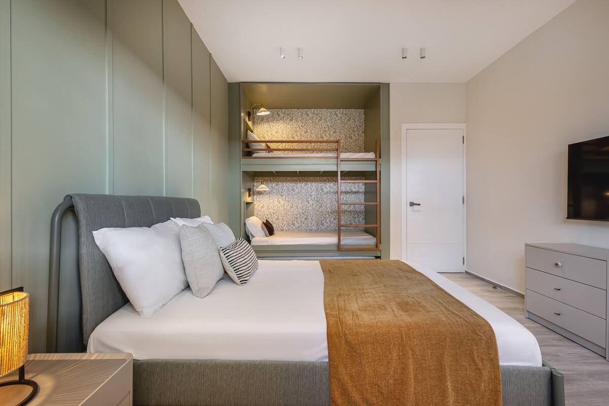 A modern bedroom with a large bed, a wardrobe, and a TV.