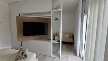A modern bedroom with a bed, a TV mounted on a wall, a sofa, and a small table with a plant.