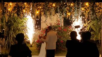 A wedding ceremony with a decorated arch and guests.