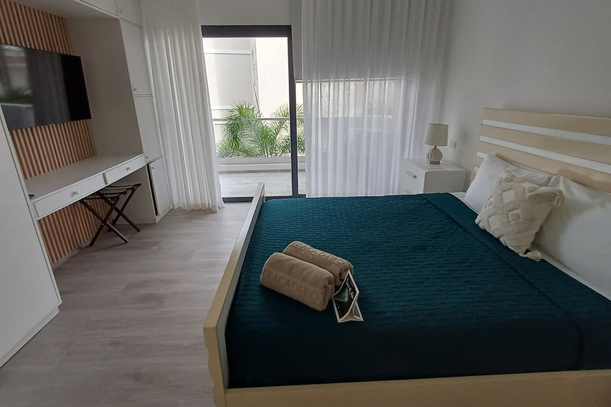 A modern hotel room with a large bed, a desk, and a TV.