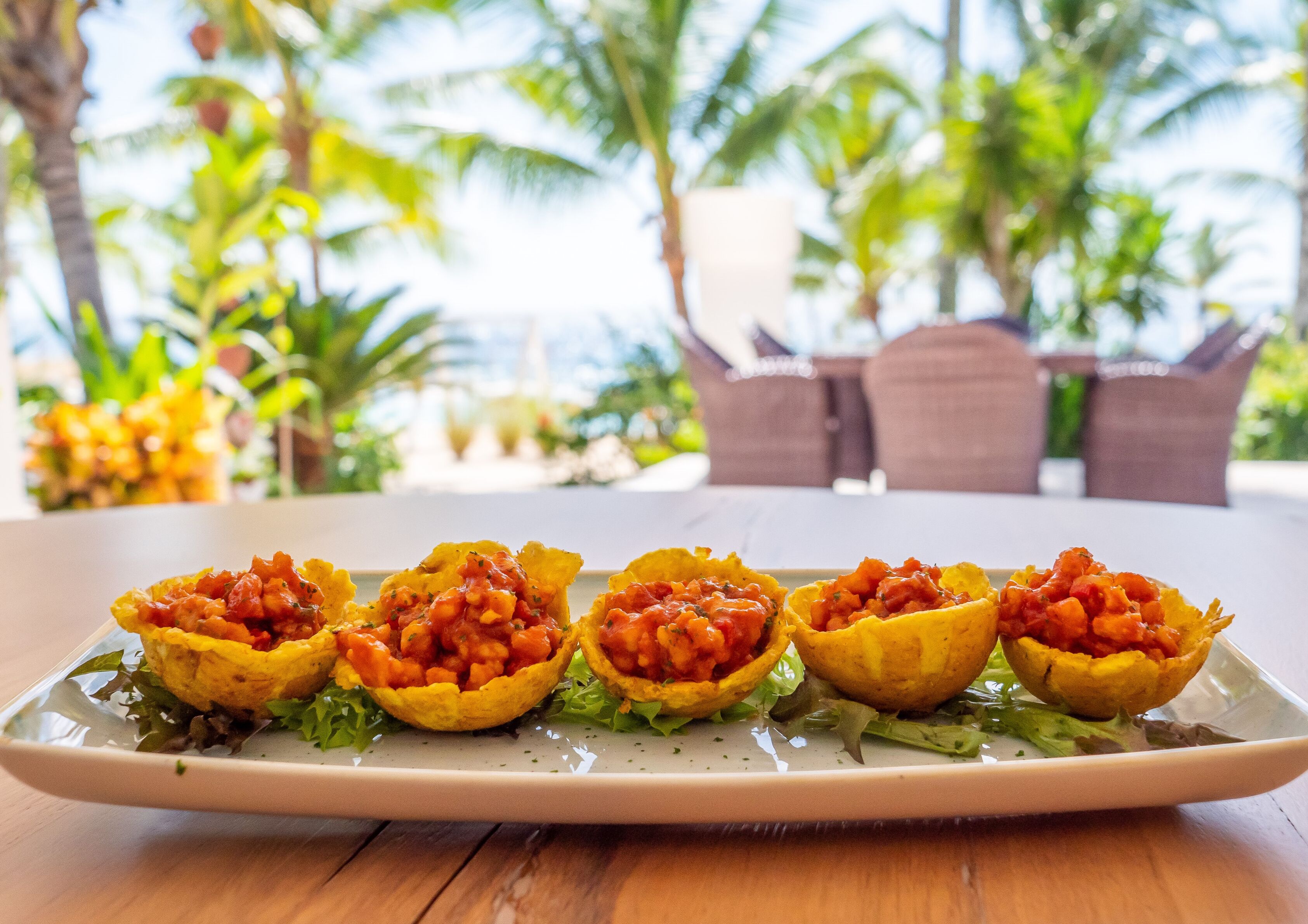 A plate of stuffed corn on the cob with a green salad on a wooden table.