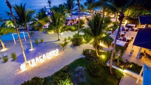 A resort with a beach area, palm trees, and a sign reading "TRAGACOMA". - TRACADERO Beach Club and Holidays Rentals (San Rafael del Yuma)