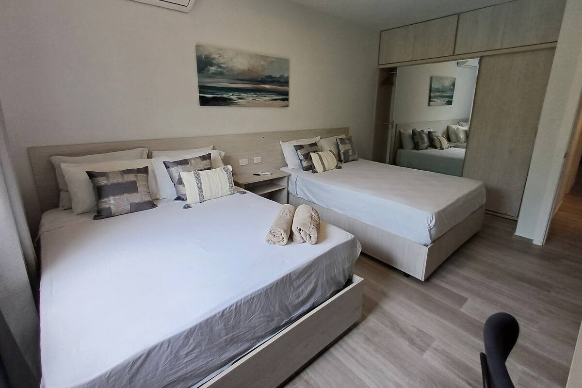 A hotel room with two beds, a painting on the wall, and a wardrobe.