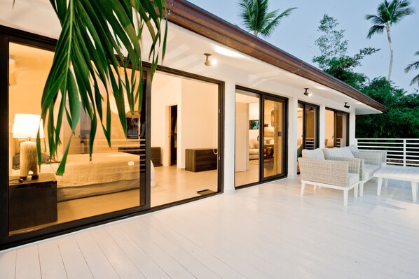 A modern house with a spacious deck, large sliding glass doors, and a cozy seating area. - TRACADERO Beach Club and Holidays Rentals (San Rafael del Yuma)