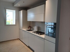 A modern kitchen with white cabinets, a gas stove, and a built-in oven.
