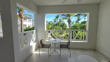 A balcony with a white railing, two chairs, a small round table, and a ceiling fan.