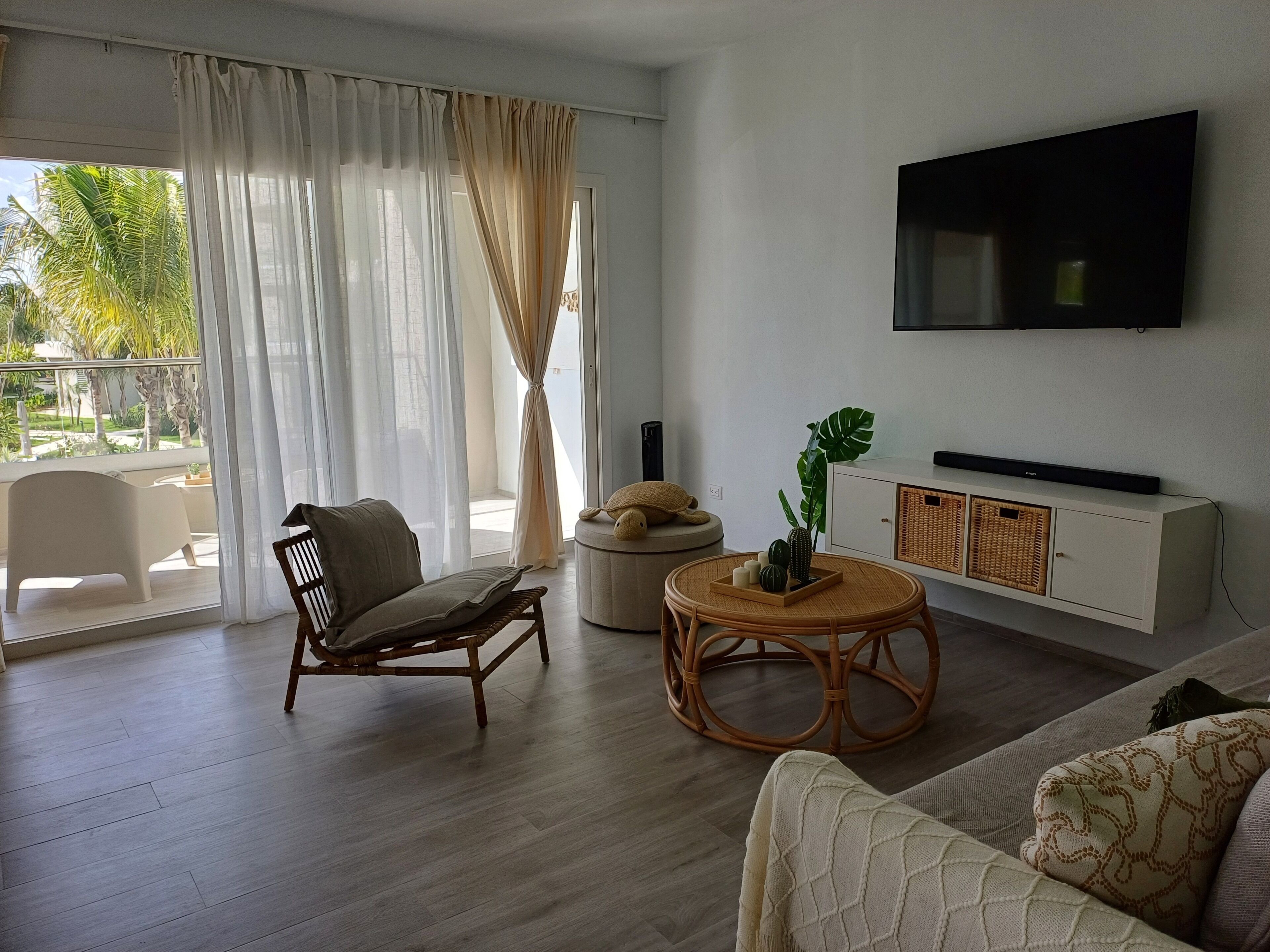 Un salon moderne avec un canapé, un fauteuil, une table basse ronde et un téléviseur fixé au mur.