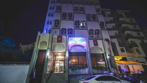 Un hotel con una entrada destacada, un letrero visible del restaurante y una escalera que lleva a la entrada.