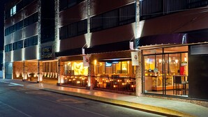 Un hôtel à étages, doté d’une terrasse et d’une façade bien éclairée.