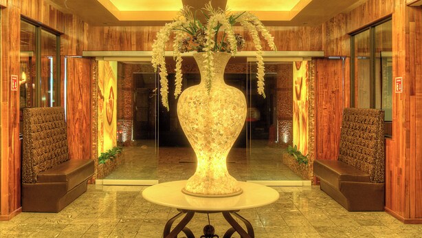 Un hall d’entrée agrémenté d’un grand vase servant de pièce maîtresse, de lambris en bois et d’un sol réfléchissant.